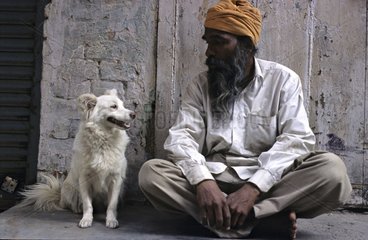Man sitting watching his dog Amritsar India