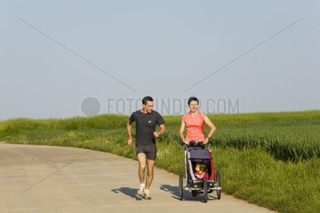 Parents current pushing their daughter in a stroller