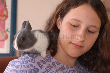 Adolescente avec un lapin gris et blanc sur l'épaule