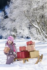 Small girl and Christmas presents on a sledge