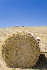 Girl playing around bundles of straw in a field France