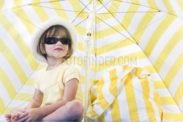 Small girl under an umbrella with sunglasses