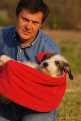 Homme portant un chien dans une serviette