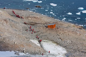 Tourists near a shelter and a colony of penguins Antarctica