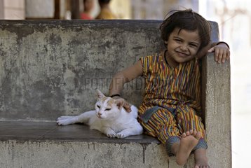 Cat lying down near a child on a bench India