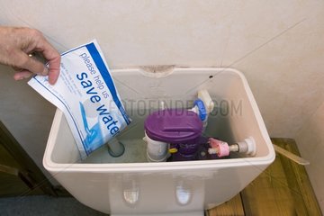 Hand placing water hippo saveaflush bag in toilet cistern