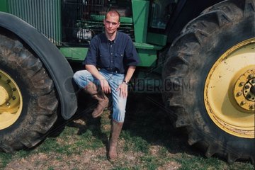 Porträt eines jungen Bauern in der Nähe seines Traktors
