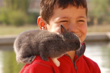 Glückliches Kind mit seinem Kaninchen auf der Schulter