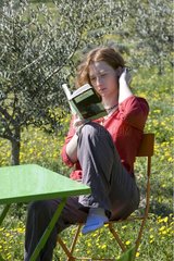 Young girl reading in the garden in Provence in spring