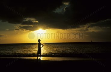 Silhouette of a boy to sunset in edge of sea