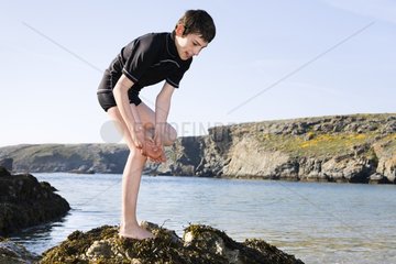Boy hurting his foot on sea side rocks