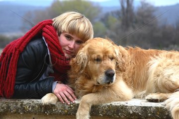 Young girl and Golden retriever lying on a wall