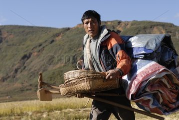 Moso farmer carrying equipment for threshing rice
