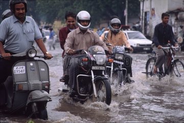 Motos roulant sur une route inondée pendant la mousson