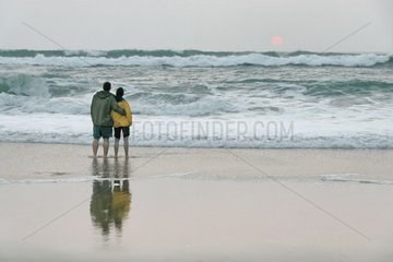 Paar  das am Strand spaziert und den Sonnenuntergang Frankreich betrachtet