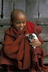 Young monk holding a kitten on his knees Burma
