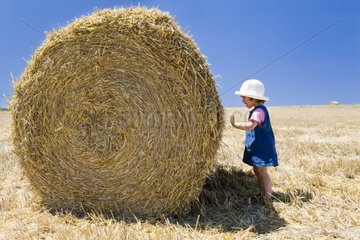 Girl playing around bundles of straw in a field France