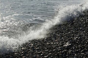 Welle auf einem Schindelstrand brechen