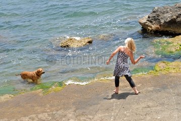 Woman playing with her dog on the beach