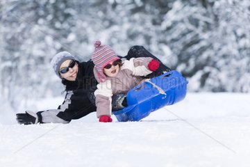 Two children in a sled on a snowy road