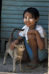 Girl with painted face caressing a cat Burma