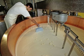 Fromager remuant à la poche le lait en train de cailler