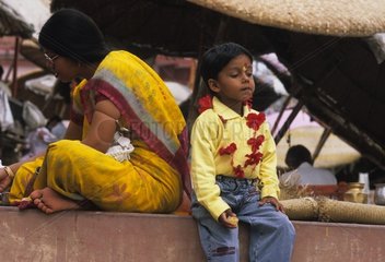 Frau und Kind sitzen auf einer niedrigen Wand Indien