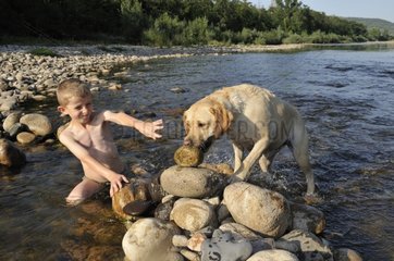 Boy playing with his dog in Eyrieux River Ardèche France