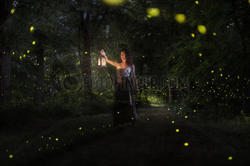 A girl is looking for the fireflies on a forest near the Po river in Italy