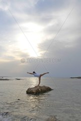 Mixed female in yoga position facing the sea Spain