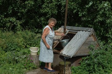Woman drawing of water to a well with beam in Russia