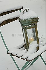 Lantern on a chair in a garden with snow