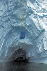 Ice tunnel. Drifting iceberg. Antarctic Peninsula.