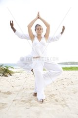 Woman and man praticing yoga on a beach in Martinique Island