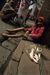 Cat lying down in the street near a girl Calcutta India