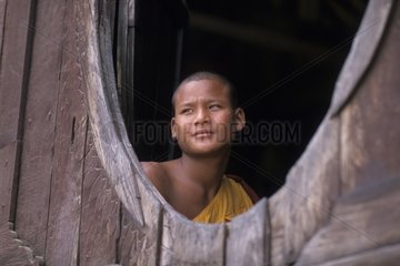 Young monk at the window of his monastery Myanmar