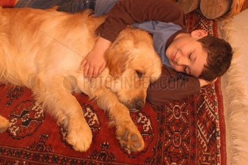 Enfant et golden retriever couchés sur un tapis persan