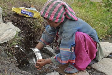 Young girl doing the dishes to a source Zanskar India