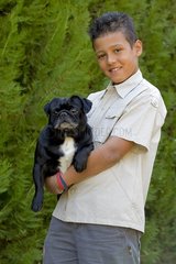 Boy holding an old Pug in his arms France