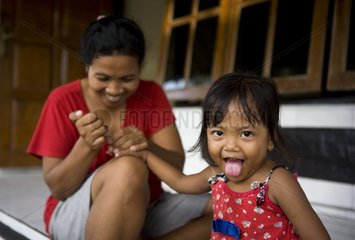 Woman cutting the nails of her daughter outside her house Bali