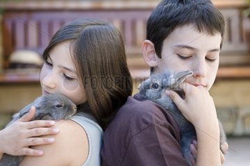 Boy and girl with their respective rabbits on the shoulders