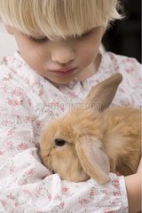 Child holding a young rabbit ram in its arms France