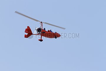Red gyroplane in blue sky - Normandy France