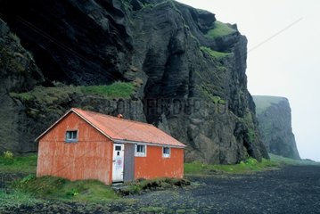 Refuge construit au pied d'une falaise volcanique Islande