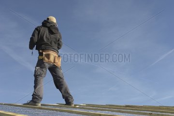 Carpenter on the roof of a built wooden house