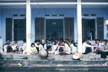 Frauen  die vor einem Haus sitzen und Vietnam sticken