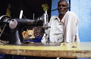 Katze neben einem Mann und seiner NÃ¤hmaschine Mysore liegt