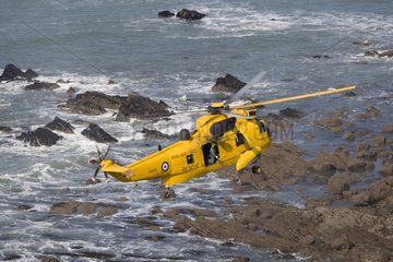 Helicopter air sea rescue above rocks at Widemouth Bay UK