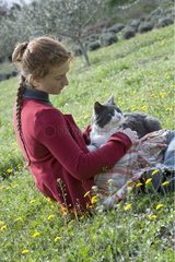 Young girl sitting in the garden with a white and gray cat