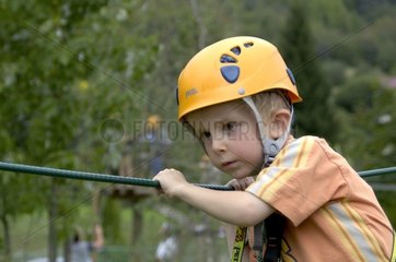 Kleiner Junge auf einem Baumstreck  der Frankreich klettern